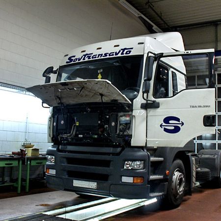 Weißer Lkw in der Werkstatt zur Reparatur mit geöffneter Motorhaube