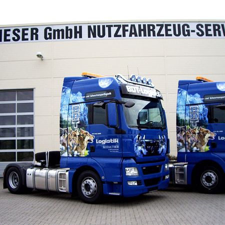 Zwei blaue Lkw vor der Werkstatthalle